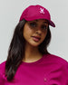 Womens Amaris Baseball Cap in vibrant magenta cotton twill with an embroidered light pink Psycho Bunny skull logo, paired with a matching magenta crewneck jersey top featuring a small embroidered Psycho Bunny logo on the left chest.