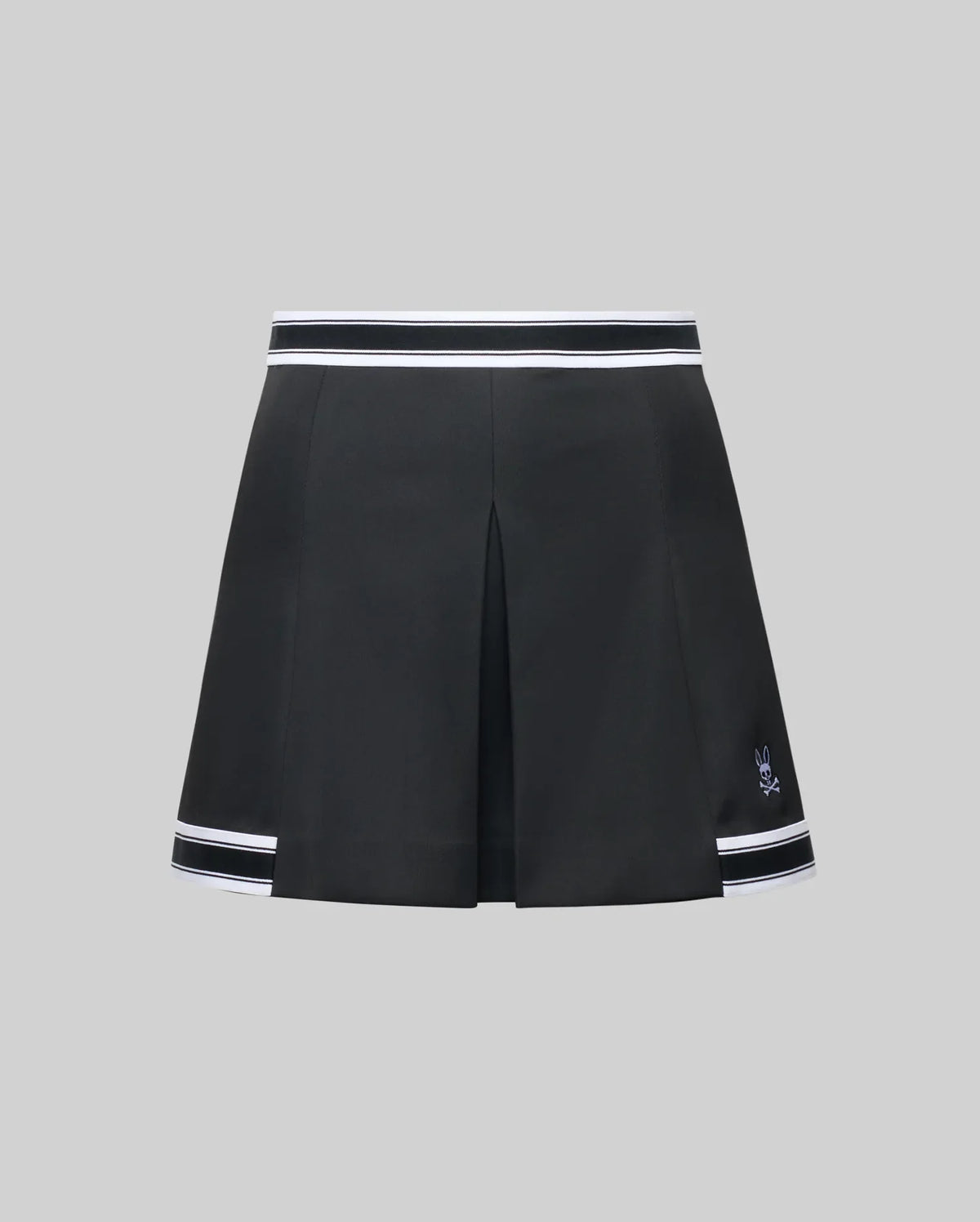 The WOMENS KNIT SKORT - WO1900001 by Psycho Bunny is a black pleated mini skort with white striped trim at the waistband and hem, plus a small white Psycho Bunny logo near the left hem, shown on a plain gray background.