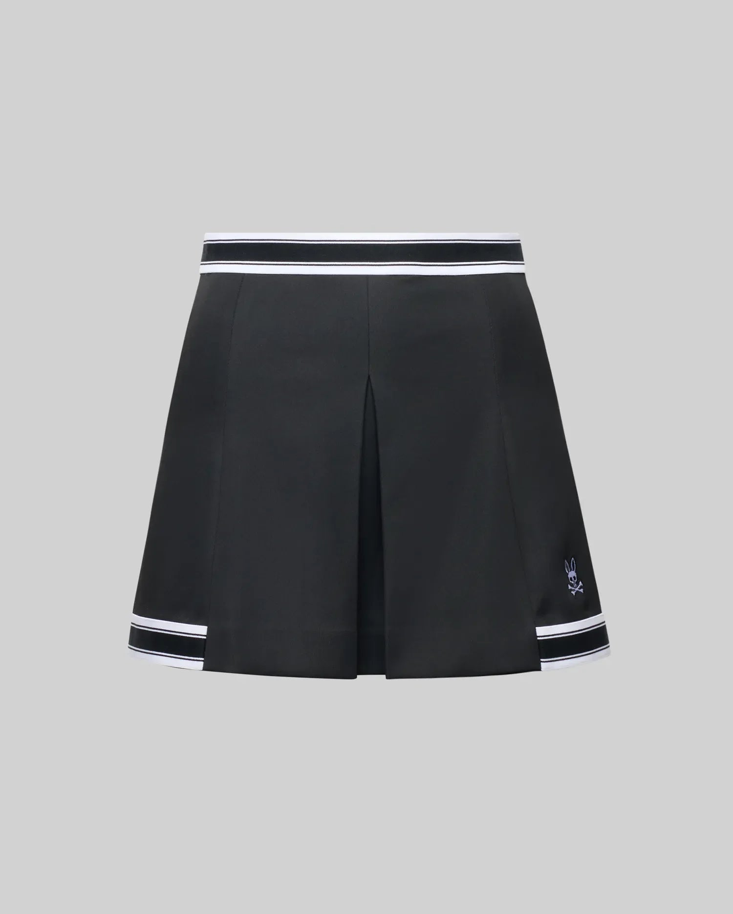 The WOMENS KNIT SKORT - WO1900001 by Psycho Bunny is a black pleated mini skort with white striped trim at the waistband and hem, plus a small white Psycho Bunny logo near the left hem, shown on a plain gray background.