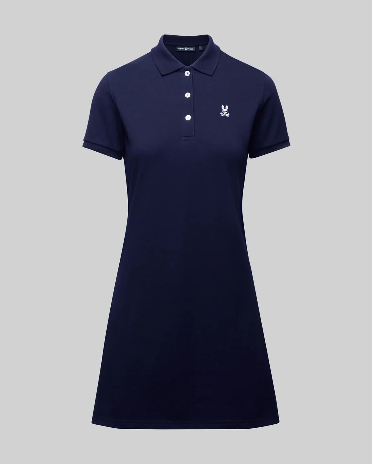 The Psycho Bunny WOMENS POLO DRESS - WO2000003 is a navy blue short-sleeve Pima polo dress with a collar, four white buttons, and a small white Bunny logo on the left chest, shown on a plain gray background.