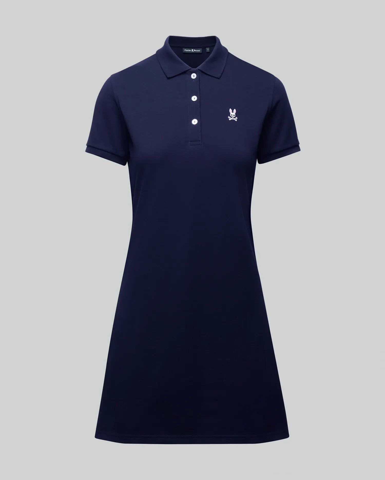 The Psycho Bunny WOMENS POLO DRESS - WO2000003 is a navy blue short-sleeve Pima polo dress with a collar, four white buttons, and a small white Bunny logo on the left chest, shown on a plain gray background.