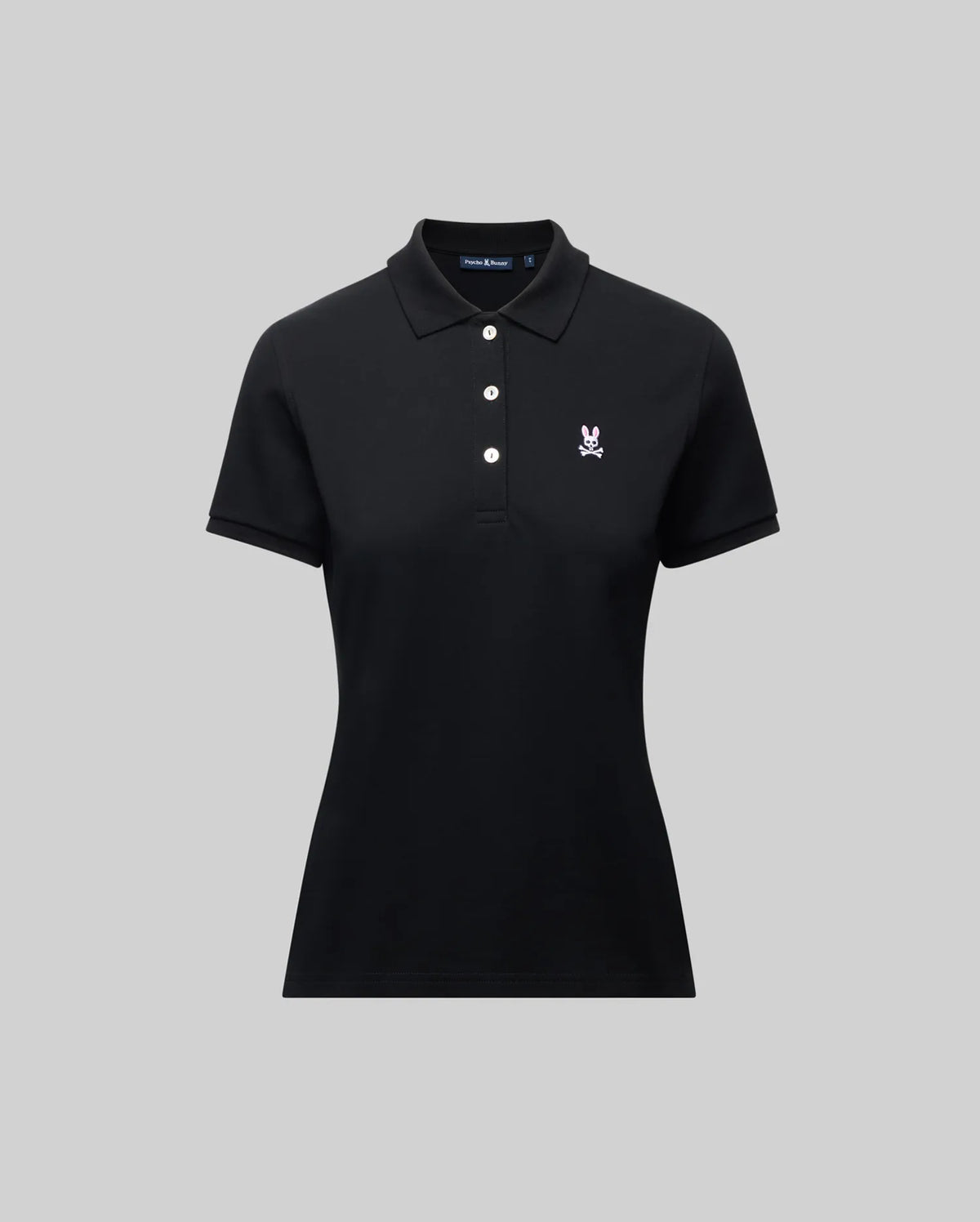 The Psycho Bunny WOMENS PIQUE POLO - WT0100003 is a black short-sleeve women’s polo with a collar, three white buttons, and a 4k-stitch embroidered Bunny logo on the left chest, shown on a plain gray background.