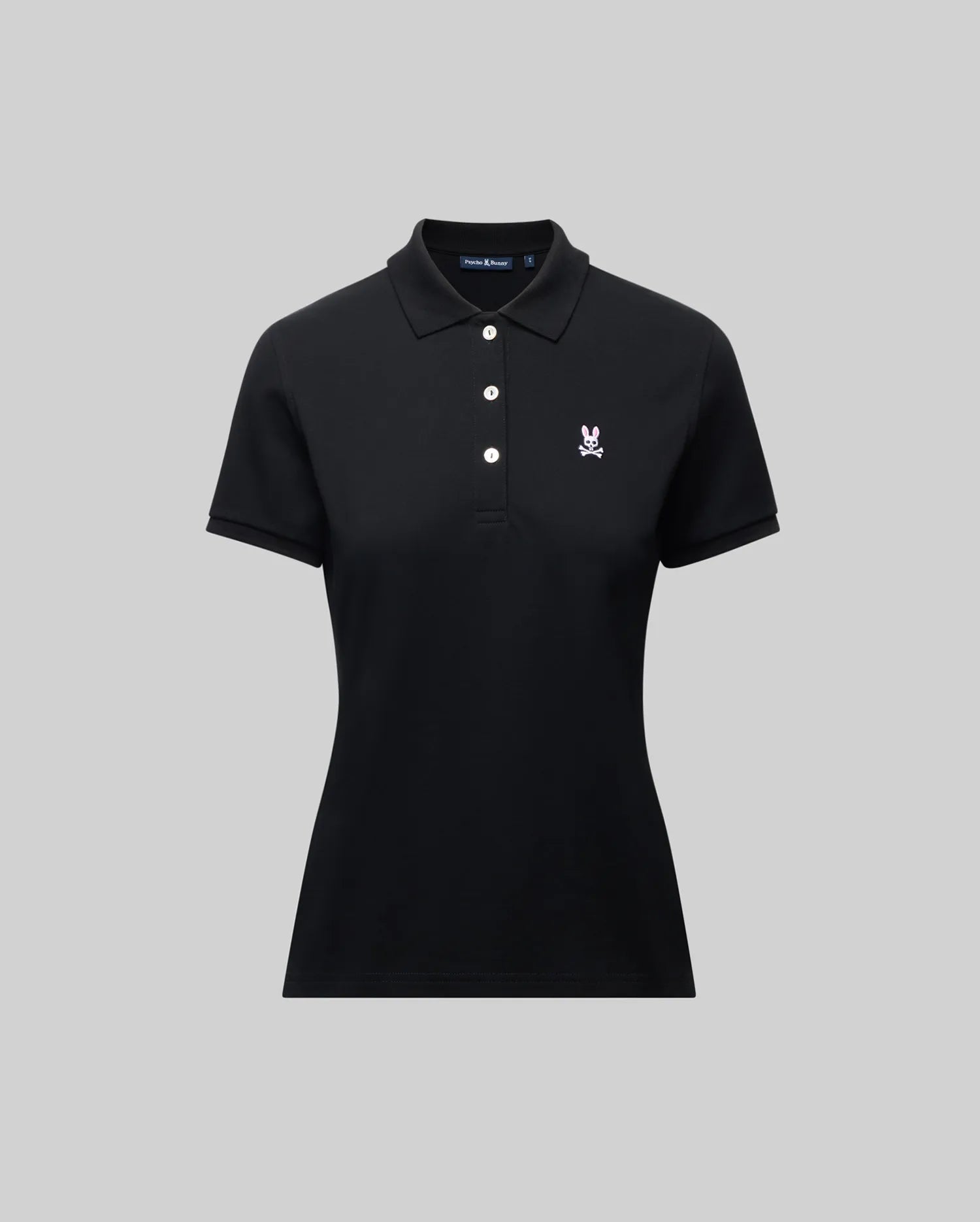 The Psycho Bunny WOMENS PIQUE POLO - WT0100003 is a black short-sleeve women’s polo with a collar, three white buttons, and a 4k-stitch embroidered Bunny logo on the left chest, shown on a plain gray background.
