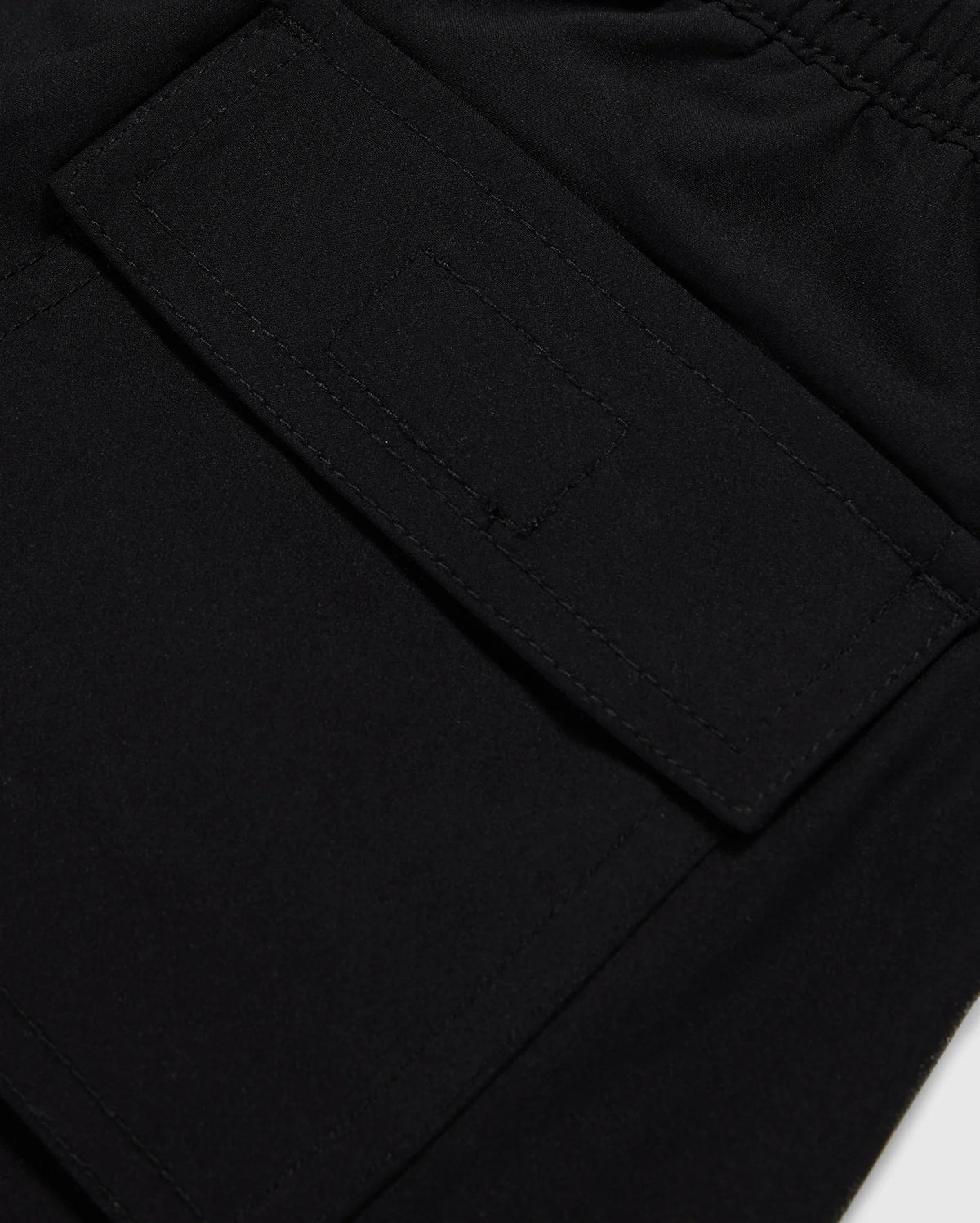 Close-up image of a black fabric pocket with a flap and Velcro closure. The pocket is attached to the KIDS MALTA HYDROCHROMIC SWIM TRUNK - B0W321B2SW by Psycho Bunny, adorned with a playful bunny pattern, and the stitching around the edges is clearly visible. The fabric appears to be smooth and durable.