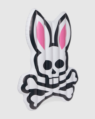 This Psycho Bunny pool float, model B6A386B200, is an inflatable PVC skeleton bunny design, ideal for a resort vacation. It showcases black and white bones, a skull face, long ears, and pink inner ear accents—perfect for lounging in the pool with style.