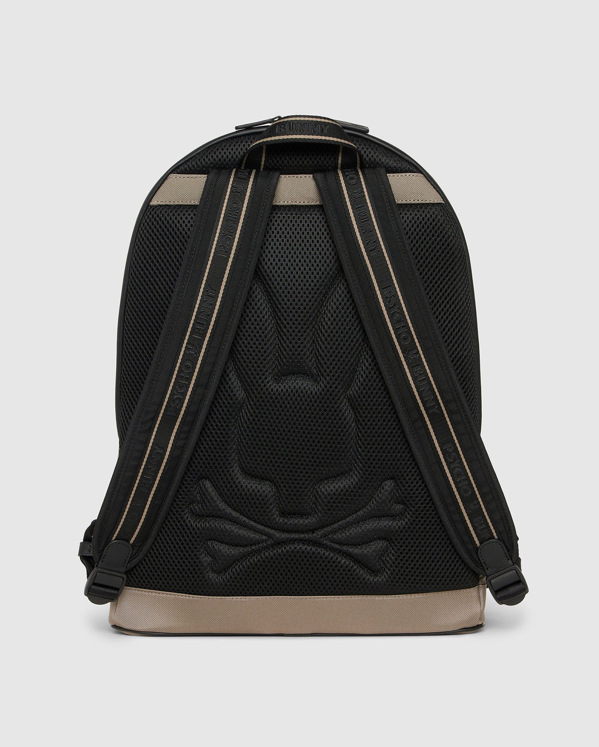The Psycho Bunny Dome Backpack (B6A628Z1BP) in black and tan is shown from the back, highlighting padded straps, a padded laptop compartment, and a textured bunny head with crossbones on the back panel.