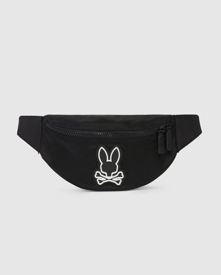 The HIP BAG - B6A631Z1BP by Psycho Bunny is a black fanny pack with a zipper and two pull tabs. It features the iconic white outline graphic of a bunny head above crossed bones on the front.