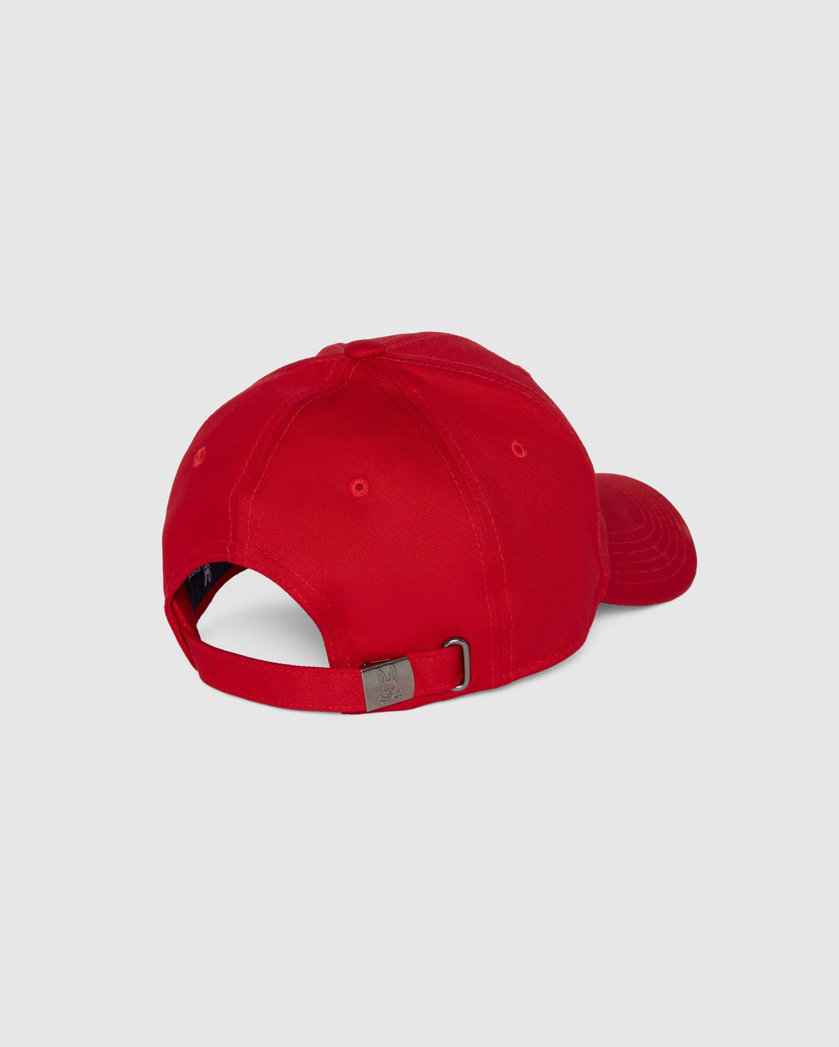 The Psycho Bunny MENS CLASSIC BASEBALL CAP - B6A816A1HT is red with a curved brim, made of six-panel cotton twill, adjustable via a metal buckle strap, and showcases an embroidered Bunny logo. It's shown from the back against a plain gray backdrop.
