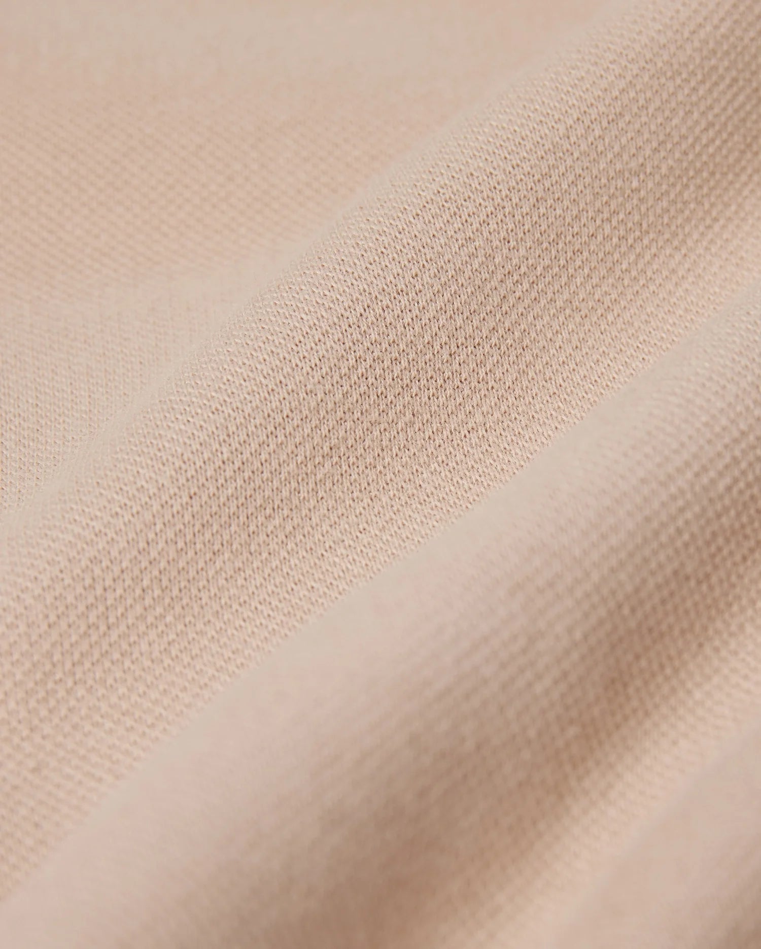 Close-up of a beige fabric with a slightly textured surface, displaying a series of gentle horizontal folds. The material appears soft and smooth, suggesting an elevated style and an exceptional on-body feel, perfect for crafting Psycho Bunny's MENS BEDFORD SHIRT JACKET - B6J290B200.