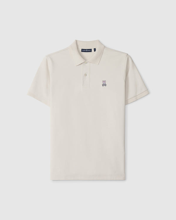 The Psycho Bunny Men's Classic Pique Polo Shirt (B6K001B200) in beige features a two-button placket, short sleeves, and an embroidered rabbit logo on the left chest. Made from soft Pima cotton, it epitomizes men's fashion essentials against a plain white background.