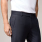 A person in a white short-sleeve polo shirt and dark Psycho Bunny MENS GABLE REGULAR FIT SPORT PANT - B6P760ARCN stands with one hand by their side. The cotton-nylon textile pants have belt loops and side pockets, with a slightly visible logo on the left pocket. The image is cropped at the shoulder and mid-thigh.