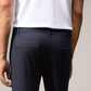 A person wearing a white short-sleeve shirt with orange and black trim at the sleeves and Psycho Bunny MENS GABLE REGULAR FIT SPORT PANT - B6P760ARCN is shown from the back. One arm hangs by their side. The background is plain and neutral.